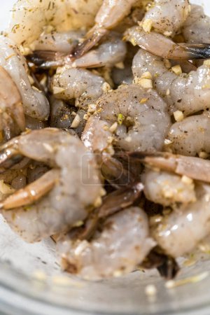 Téléchargez les photos : Faire mariner les crevettes crues avec de l'ail et des épices pour préparer des pâtes aux crevettes avec des épinards.. - en image libre de droit
