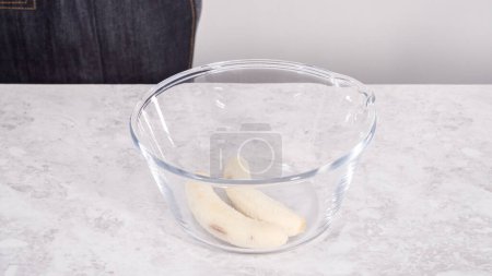 Photo for Step by step. Smashing riped bananas in a glass mixing bowl to prepare coconut banana pancakes. - Royalty Free Image