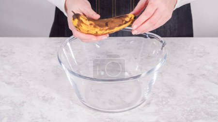 Téléchargez les photos : Pas à pas. Écraser les bananes hachées dans un bol à mélanger en verre pour préparer des crêpes à la banane à la noix de coco. - en image libre de droit