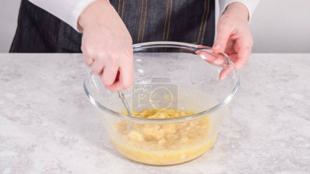 Photo for Step by step. Mixing ingredients in a glass mixing bowl to prepare coconut banana pancakes. - Royalty Free Image