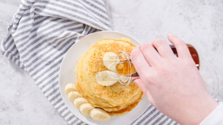 Photo for Flat lay. Step by step. Stack of freshly baked coconut banana pancakes garnished with sliced bananas, toasted coconut, and maple syrup. - Royalty Free Image