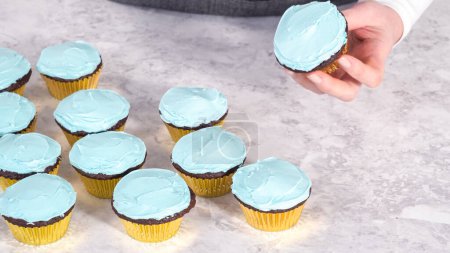 Téléchargez les photos : Pas à pas. Cueillette bleu crème au beurre glaçage sur le dessus des cupcakes au chocolat. - en image libre de droit