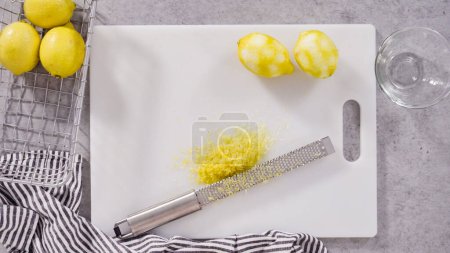 Pose plate. Zesting citrons biologiques pour faire cuire un gâteau de livre de citron.