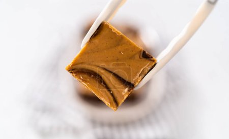 Photo for Holding chocolate fudge with peanut butter swirl piece with kitchen tongs. - Royalty Free Image
