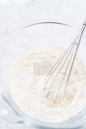 Photo for Mixing ingredients in a glass mixing bowl to prepare coconut banana pancakes. - Royalty Free Image