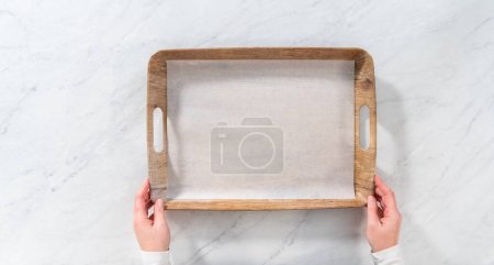 Téléchargez les photos : Pose plate. Doublure d'un plateau de service en bois avec feuille de papier parchemin pour préparer un panneau de beurre végétarien pour une fête. - en image libre de droit