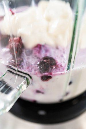 Téléchargez les photos : Mixing ingredients in kitchen blender to prepare mixed berry boba smoothie. - en image libre de droit