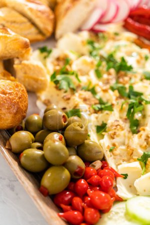 Téléchargez les photos : Une grande planche de beurre végétarienne avec des légumes frais et marinés et une baguette française tranchée pour une fête. - en image libre de droit