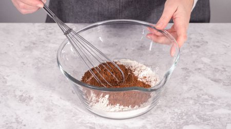 Téléchargez les photos : Pas à pas. Mélanger les ingrédients dans un bol à mélanger en verre pour préparer le gâteau bundt en velours rouge. - en image libre de droit