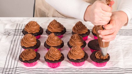Photo for Step by step. Piping chocolate ganache frosting on top of chocolate cupcakes. - Royalty Free Image