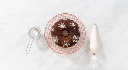 Photo for Flat lay. Decorating gingerbread bundt cake with caramel filling, buttercream frosting, and powdered sugar dusting. - Royalty Free Image