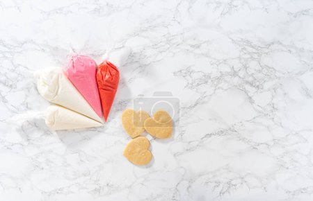 Photo for Flat lay. Homemade royal icing in piping bags ready to decorate sugar cookies on the kitchen counter. - Royalty Free Image