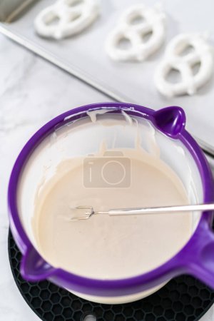 Foto de Dipping pretzels twists into melted chocolate to make red, white, and blue chocolate-covered pretzel twists. - Imagen libre de derechos