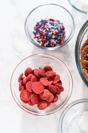 Téléchargez les photos : Ingrédients mesurés dans des bols à mélanger en verre pour préparer des bretzels rouges, blancs et bleus recouverts de chocolat. - en image libre de droit