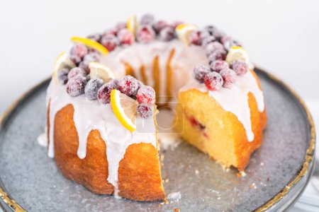 Photo for Sliced lemon cranberry bundt cake decorated with sugar cranberries and lemon wedges on a cake stand. - Royalty Free Image