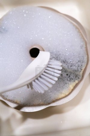 Téléchargez les photos : Nettoyage sale casserole à gâteau bundt en aluminium avec brosse à gommage de cuisine dans un évier de cuisine. - en image libre de droit