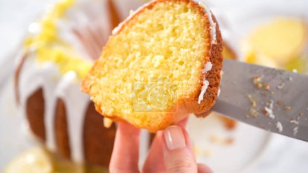 Téléchargez les photos : Pas à pas. Trancher le gâteau de lapin de citron décoré avec du zeste de citron sur un stand de gâteau. - en image libre de droit