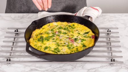 Step by step. Freshly baked spinach and ham frittata in cast iron skillet.