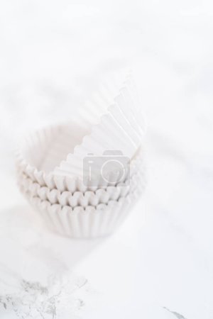 Téléchargez les photos : Nouvelles doublures de cupcake en papier blanc sur le comptoir de la cuisine. - en image libre de droit