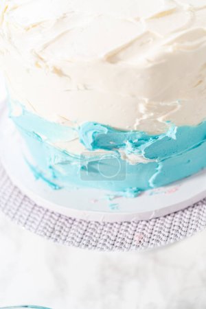 Photo for Covering 3 layer vanilla cake with buttercream frosting to create mermaid-themed 3 layer vanilla cake. - Royalty Free Image