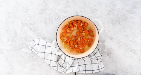 Téléchargez les photos : Pose plate. Sauter les légumes dans un four hollandais en fonte émaillée pour faire cuire la soupe aux pois cassés. - en image libre de droit