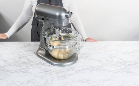 Téléchargez les photos : Mélange d'ingrédients dans un mélangeur électrique de cuisine pour cuire des biscuits sablés en forme de panda avec glaçage au chocolat. - en image libre de droit