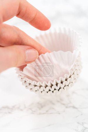 Foto de Nuevos revestimientos de cupcakes de papel blanco en el mostrador de la cocina. - Imagen libre de derechos