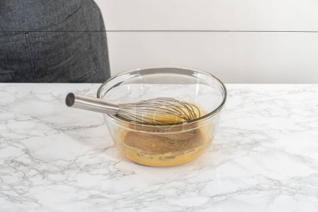 Foto de Mezclar ingredientes húmedos en un tazón de vidrio grande para hornear magdalenas de semillas de amapola de limón. - Imagen libre de derechos