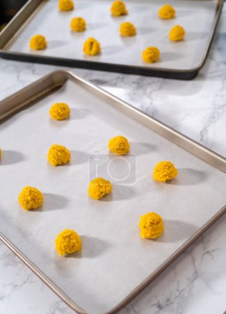 Photo for Lemon Cookies with White Chocolate. Scooping cookie dough with dough scoop into a baking sheet lined with parchment paper to bake lemon cookies with white chocolate. - Royalty Free Image