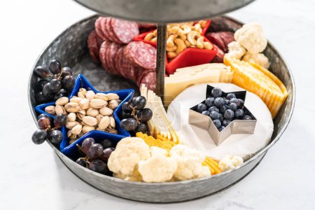 Photo for Building July 4th charcuterie board on a two-tiered serving metal stand. - Royalty Free Image