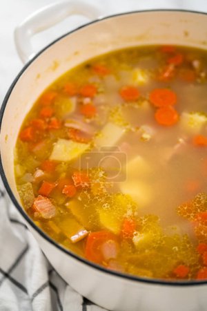 Photo for Cooking split pea soup in enameled cast iron dutch oven. - Royalty Free Image