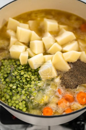 Téléchargez les photos : Cuisson de soupe de pois cassés dans un four hollandais en fonte émaillée. - en image libre de droit