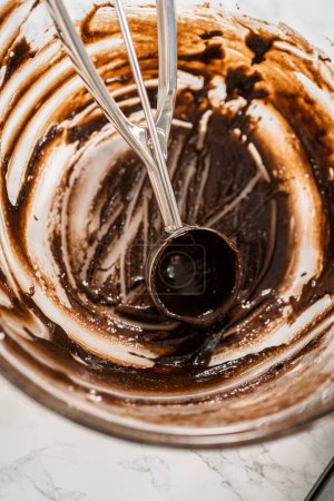 Foto de Recoger masa de pastel con cuchara de masa en forros de papel de magdalena para hornear pasteles de menta de chocolate. - Imagen libre de derechos