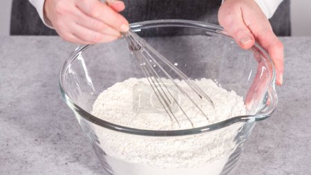 Téléchargez les photos : Pas à pas. Mélanger les ingrédients dans un bol de mélange en verre pour préparer le gâteau bundt aux canneberges au citron. - en image libre de droit