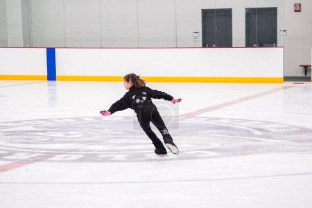 Téléchargez les photos : Petite fille pratiquant le patinage artistique à la patinoire intérieure. - en image libre de droit