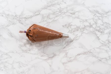 Photo for Flat lay. Chocolate ganache frosting in a piping bag with a metal tip. - Royalty Free Image