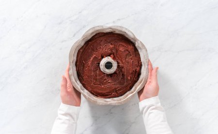 Photo for Flat lay. Filling metal bundt cake pan with cake butter to bake red velvet bundt cake with cream cheese glaze - Royalty Free Image