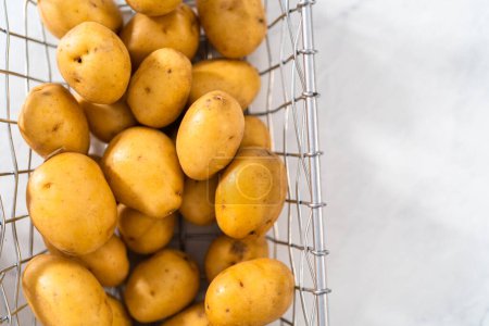 Photo for Pressure Cooker Baked Potatoes. Raw potatoes in a wire basket on the kitchen counter. - Royalty Free Image