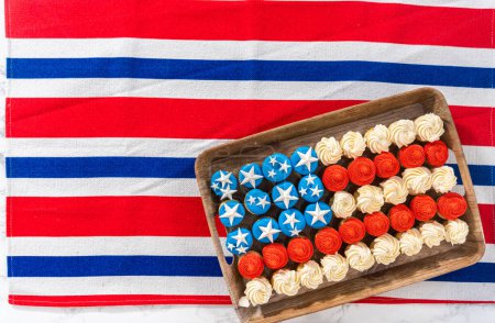 Foto de Flat lay. Arranging mini vanilla cupcakes in the shape of the American flag. - Imagen libre de derechos