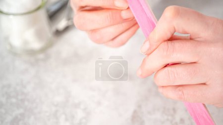 Téléchargez les photos : Femme finissant sa manucure à la maison avec des outils de manucure simples. Clous de classement avec un filtre à ongles. - en image libre de droit