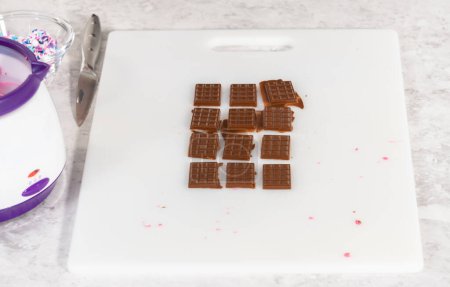 Foto de Extracción de mini chocolates del molde de chocolate de silicona en una tabla de cortar blanca. - Imagen libre de derechos