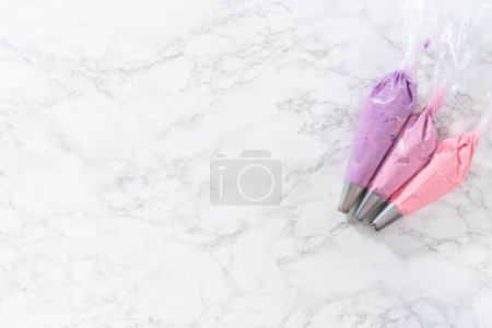 Photo for Flat lay. Ombre pink buttercream frosting in a piping bag with a jumbo metal piping tip. - Royalty Free Image