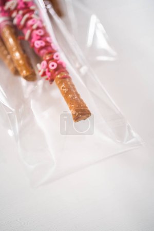 Foto de Barras de pretzel cubiertas de chocolate decoradas con aspersiones en forma de corazón para el Día de San Valentín empaquetadas en bolsas transparentes. - Imagen libre de derechos