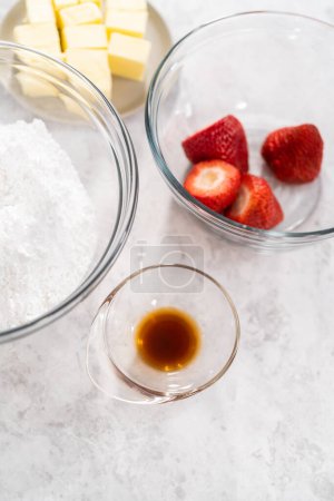 Foto de Ingredientes en un vaso mezclando cuencos para preparar el glaseado de crema de mantequilla de fresa. - Imagen libre de derechos
