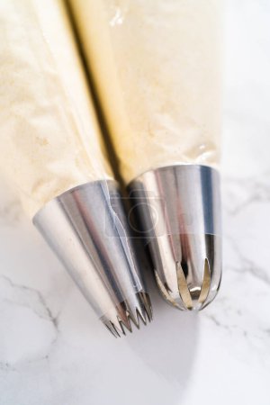 Photo for Piping bags with jumbo metal piping tips filled in with Jumbo metal piping tip for cupcake frosting. - Royalty Free Image