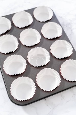 Téléchargez les photos : Poêle à cupcake doublure avec doublures en papier d'aluminium cupcake pour cuire des cupcakes en velours rouge avec glaçage ganache au chocolat blanc. - en image libre de droit