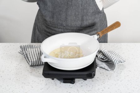 Téléchargez les photos : Faire frire l'oignon sur une poêle antiadhésive pour faire des empanadas petit déjeuner avec des œufs et des patates douces. - en image libre de droit