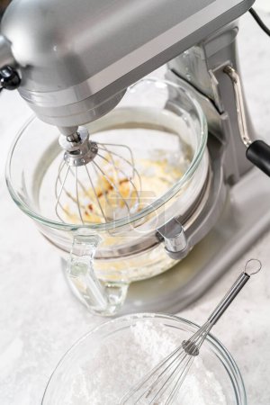 Foto de Batiendo crema de mantequilla de fresa glaseado en una batidora eléctrica independiente con un accesorio de batidor. - Imagen libre de derechos