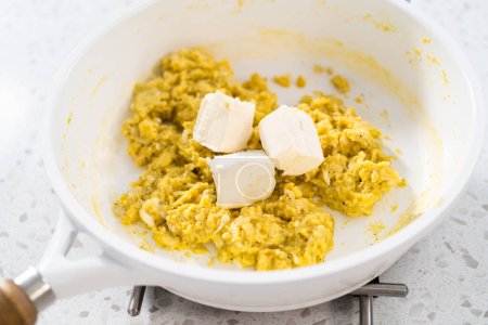 Foto de Freír los huevos en una sartén antiadherente para hacer empanadas de desayuno con huevos y batatas. - Imagen libre de derechos