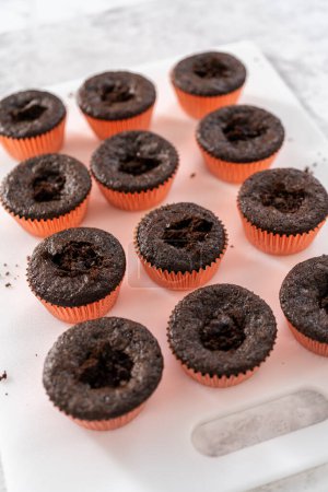 Foto de Llenado de cupcakes de chocolate recién horneados con relleno de fresas. - Imagen libre de derechos